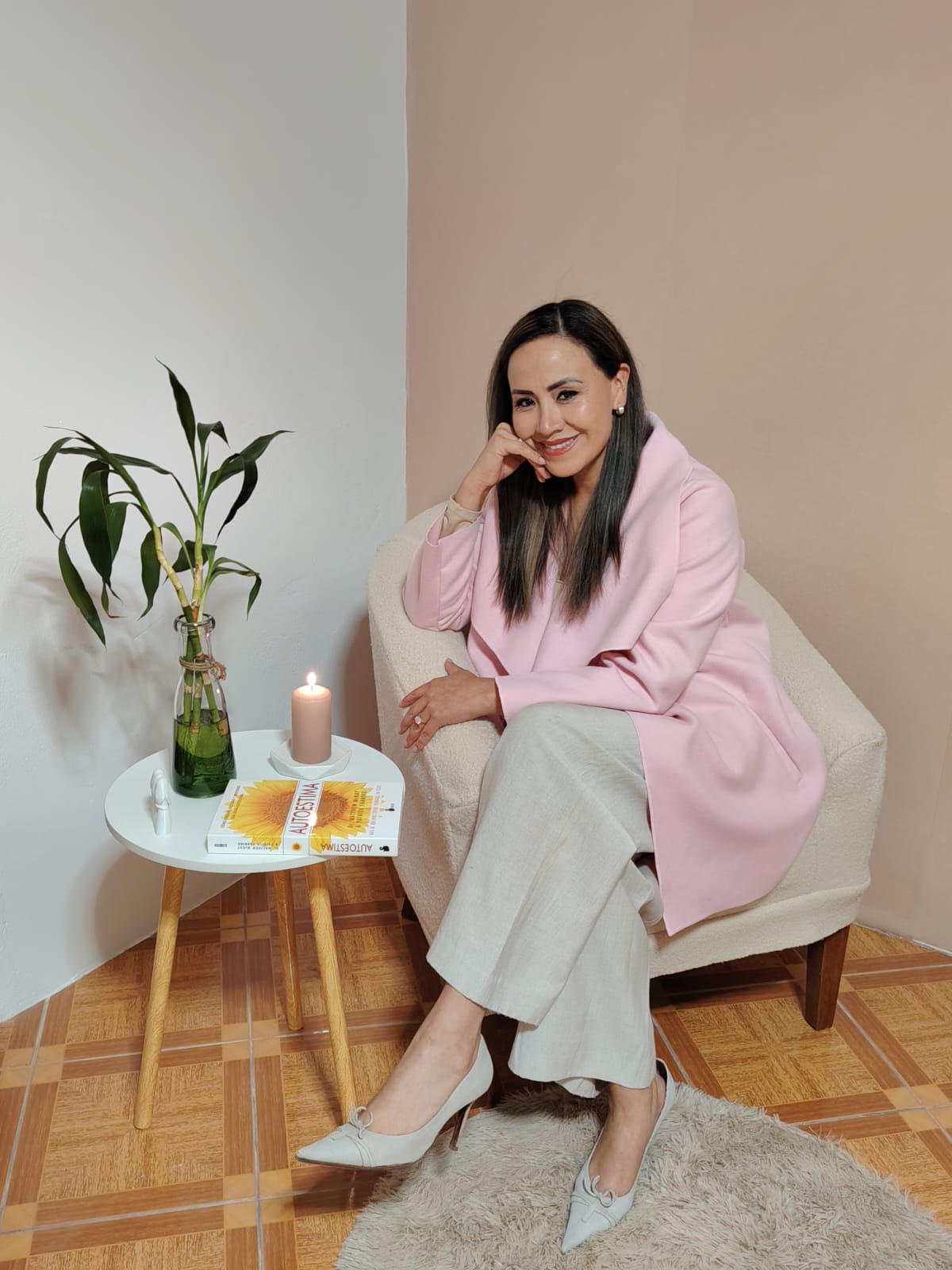 Yoyce Soto sentada en su consultorio, con una vela encendida y un libro de autoestima